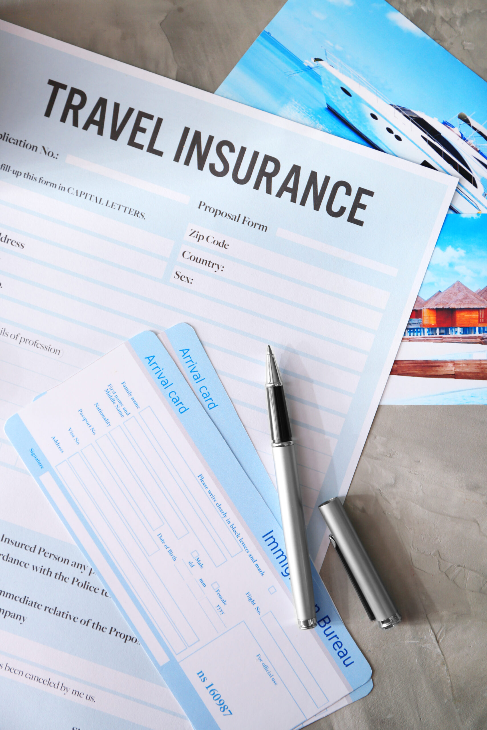 Arrival cards and pen on blank travel insurance form, closeup